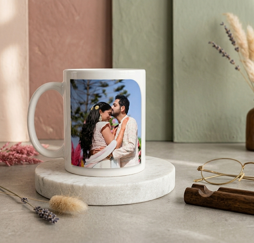 A printed photo mug with a photo of a couple, kept on a marble coaster with decorative elements.